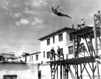 A high diver makes a giant, albeit graceful, leap into the pool. Below, a group of swimmers gets set during a 1942 swim meet.