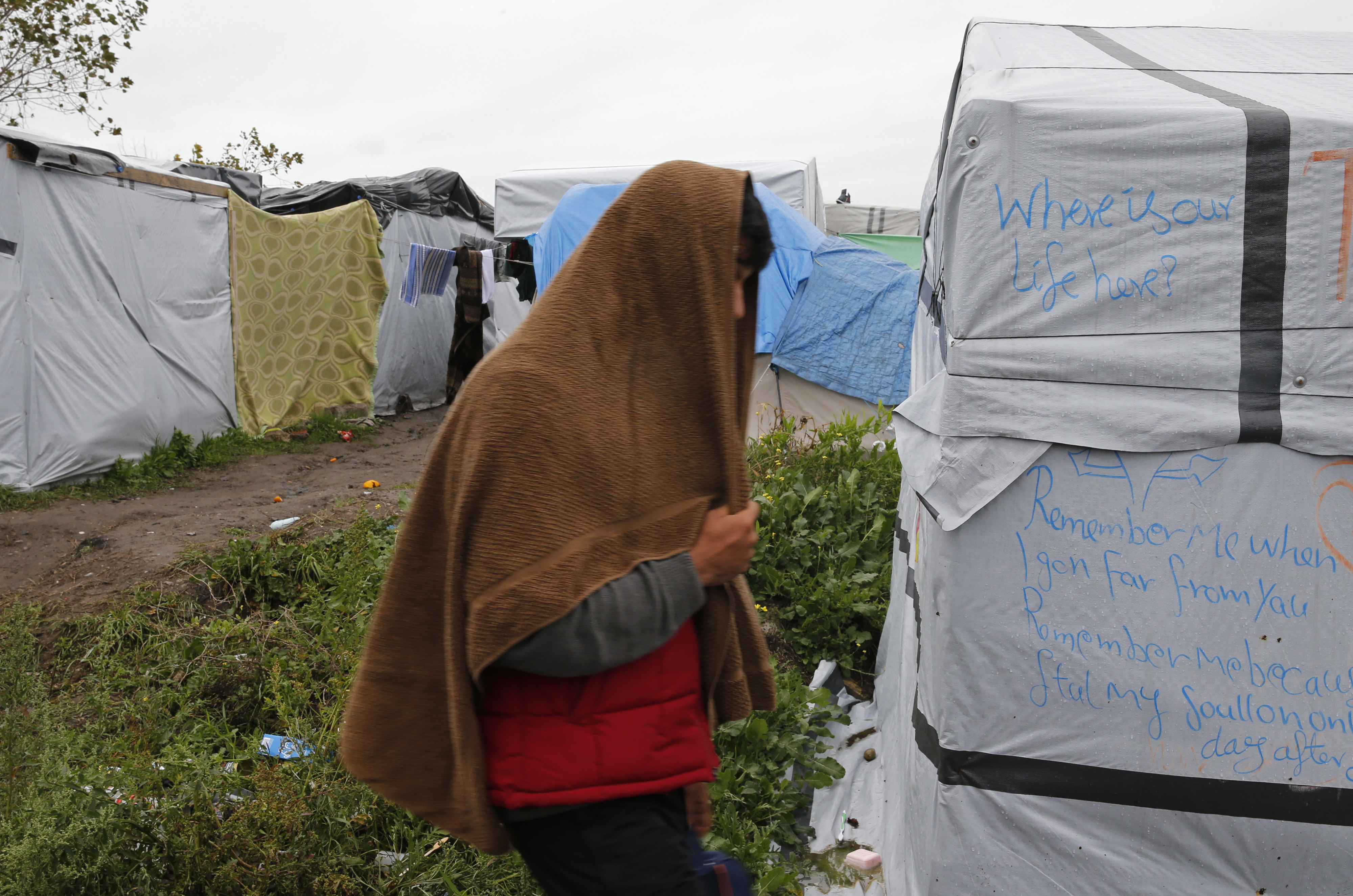 A migrant walks past tents and shelters in the makeshift camp called the "New Jungle" as unseasonably cool temperatures arrive in Calais, northern France, October 21, 2015. The number of migrants camped on France's north coast near Calais has doubled to around 6,000 in recent weeks, boosted by an influx across Europe's borders. Migrants and refugees are camped in Calais, fleeing war and poverty in the Middle East, Africa and Asia and now living in the jungle. Most of them are hoping to make the crossing to England.   REUTERS/Pascal Rossignol - RTS5GCR