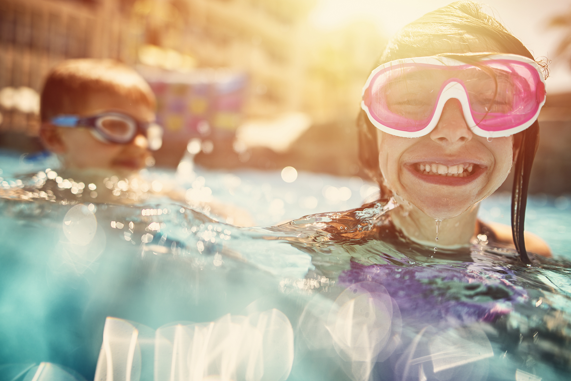Kids swimming, laughing and having fun in hotel resort pool.