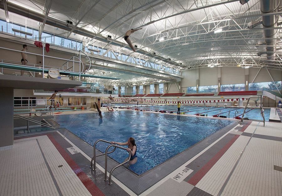 Suitable to host competitions, the facility boasts two full-color video boards, state-of-the-art timing systems, and a high-quality sound system. The bleachers accommodate up to 750 and wrap the finish line on three sides so spectators feel more connected to the action. With separate tanks, divers can enjoy warmer temperatures, while swimmers in the competition pool can work in cooler water. Outside the immediate swimming area are separate team and visitor locker rooms, an event meeting room, wet classroom, and accommodations for multiple kinds of media coverage.